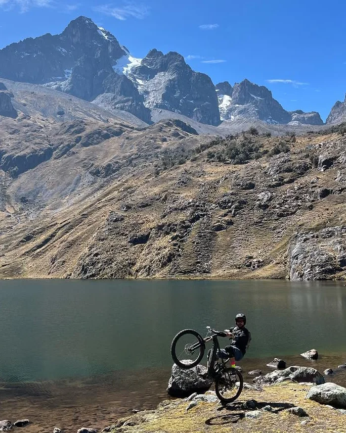 A cyclist lifts the front wheel over rocks, showing control and technique in a demanding natural setting.