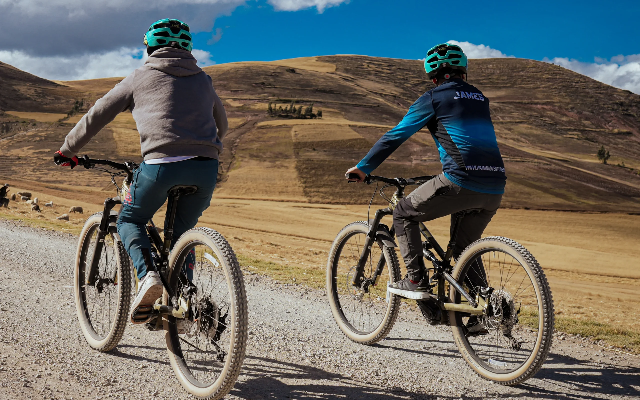 Mountain bikers ride a rural road in the Sacred Valley near Cusco, Peru, with open landscapes and wide views along the route.