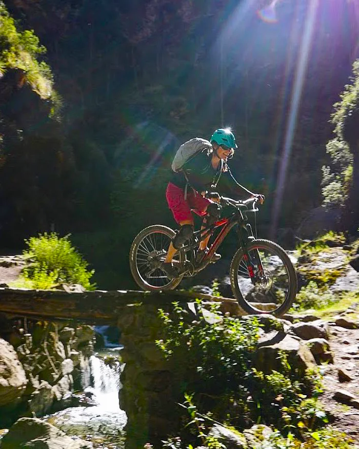 La escena captura un momento de mountain bike técnico, donde el equilibrio y el control son fundamentales.