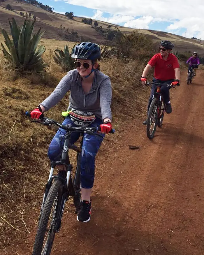 Un grupo de ciclistas recorre un camino rural de tierra mientras practica mountain bike en un entorno andino abierto.