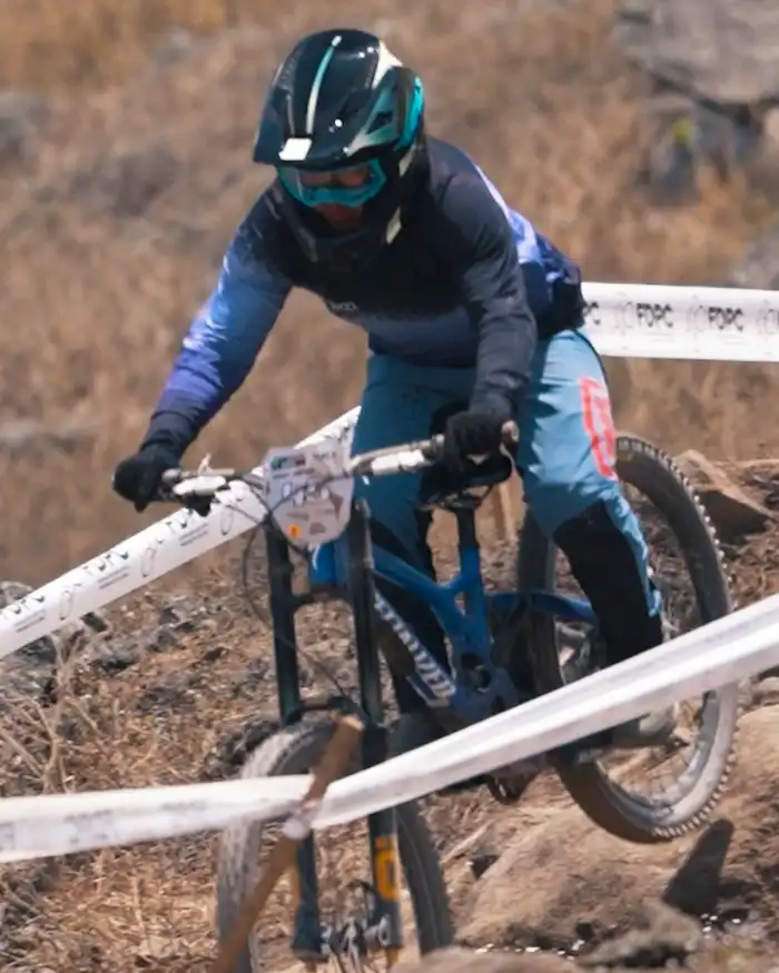 Mountain biker descends a rocky technical trail in Cusco, Peru, navigating dry terrain, ledges, and loose stones with controlled braking.