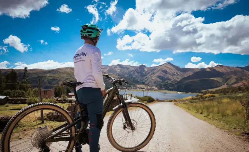 MTB start point near Laguna Sapacto in Lamay highlands, Sacred Valley, Cusco, Peru, with riders and bikes under bright blue sky.