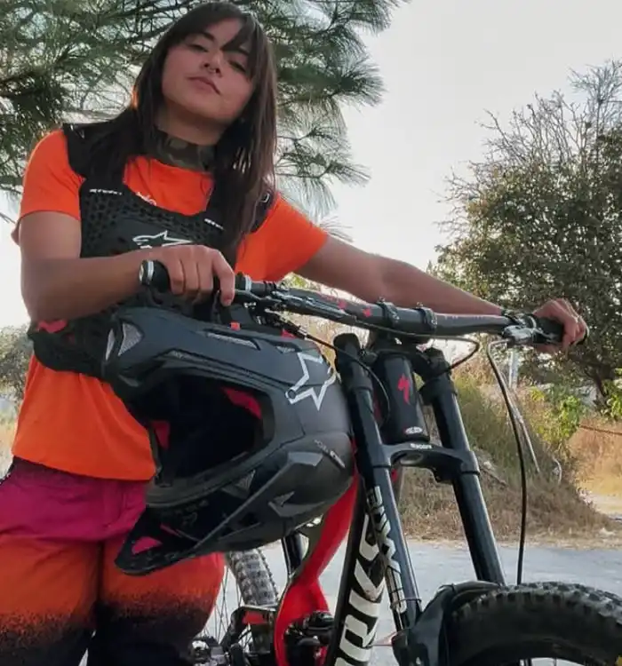 La ciclista sostiene un casco integral, lo que indica que practica MTB de forma técnica y responsable.