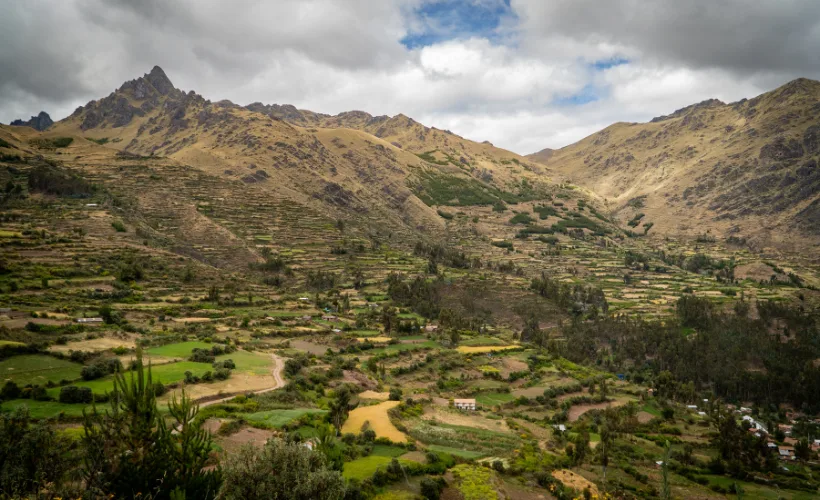 Paisaje amplio del valle desde las alturas de Lamay en el Valle Sagrado, Cusco, Perú, con colinas, montañas lejanas y cielo abierto.