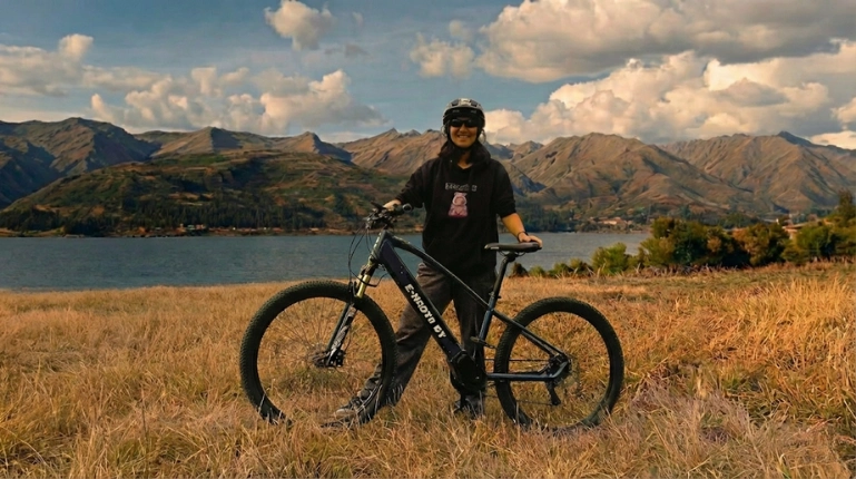 A smiling woman poses with her bike after a scenic Cusco en E-bike ride through the mountains.