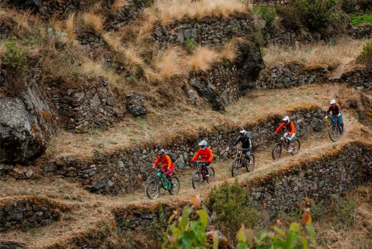 Mountain bikers riding single file down the stone terraces of the Inka Avalanche route