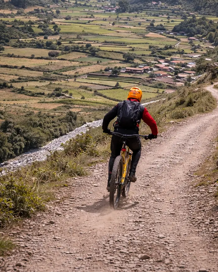 El ciclista mantiene una postura estable, con el cuerpo ligeramente hacia atrás para controlar la velocidad en el descenso.