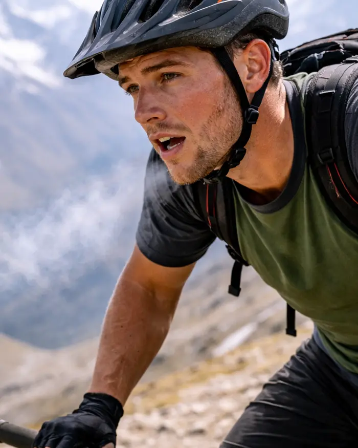 A mountain biker stopped at a high altitude area, surrounded by an open mountainous landscape.