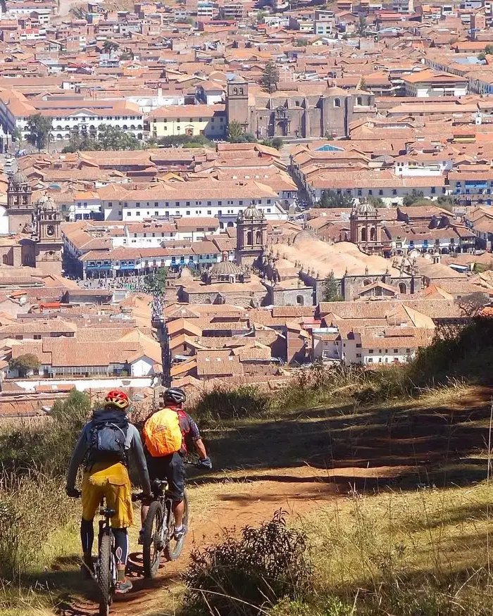 The dirt trail winds through grasslands, offering a smooth descent toward the city of Cusco.