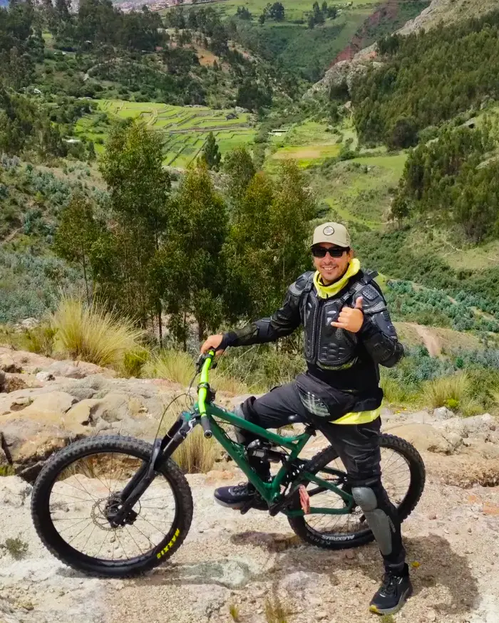 The full suspension bike is positioned on rocky terrain, typical of Andean trails in Cusco.