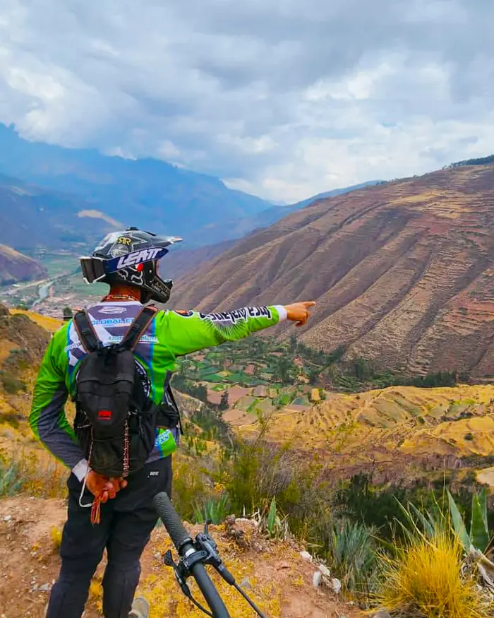 El rider analiza el terreno con calma, identificando posibles líneas en la montaña frente a él.