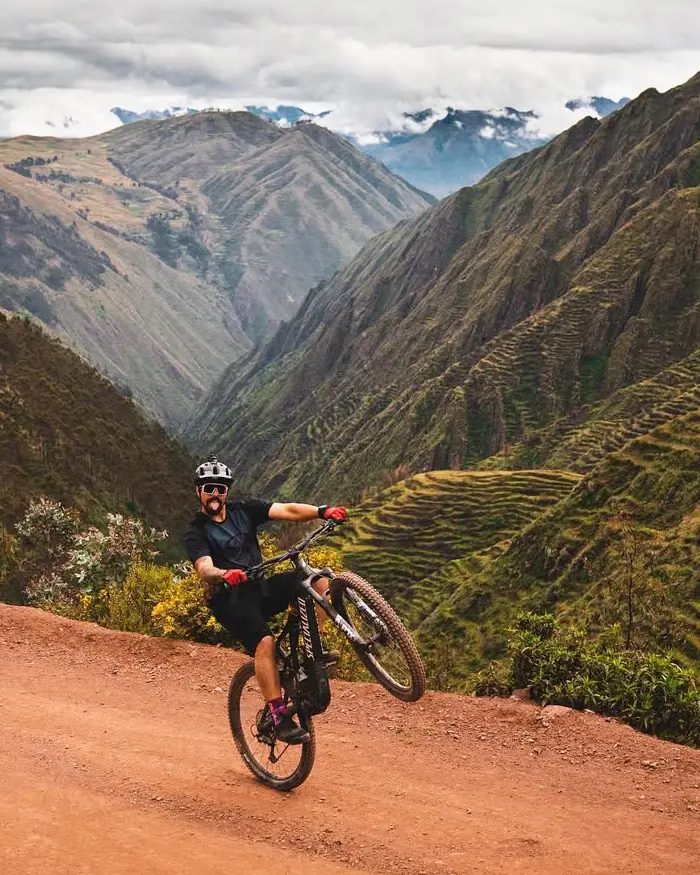 El rider ejecuta un wheelie con confianza, mostrando habilidad sobre un terreno amplio y seco.