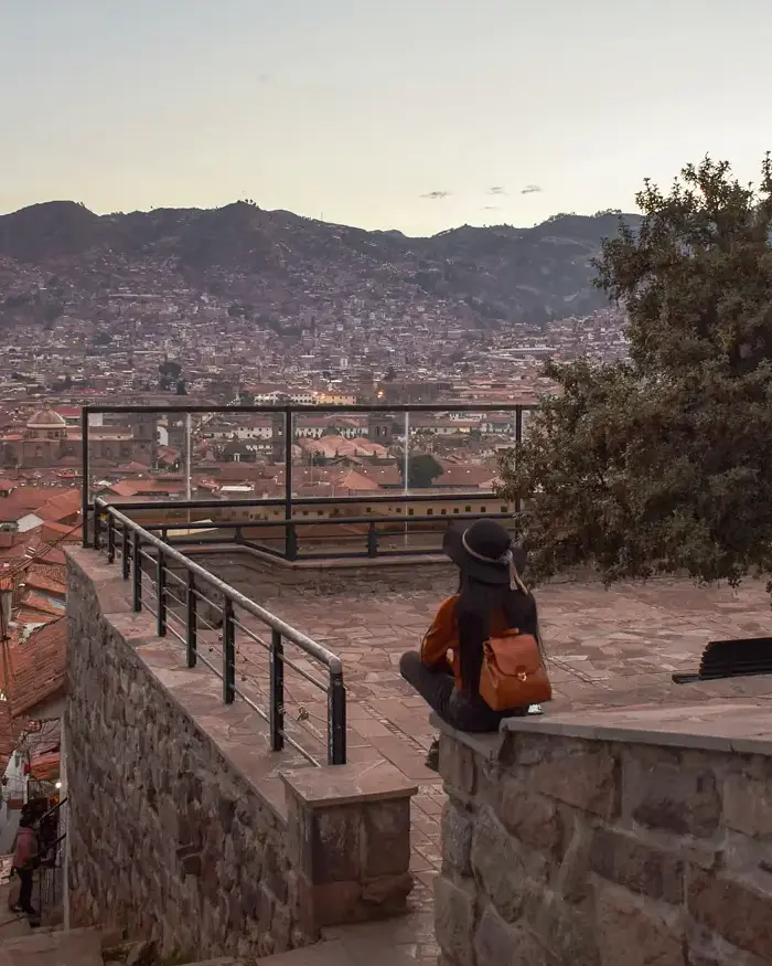 The urban landscape features characteristic red rooftops surrounded by hills that highlight the Andean geography.