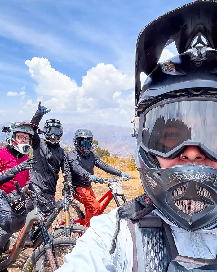They are all wearing full face helmets, goggles, and body protection, ready for technical descents.